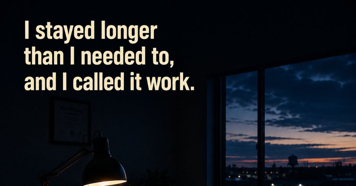 A desk at dusk with a single lamp lit, and the words: I stayed longer than I needed to, and I called it work.