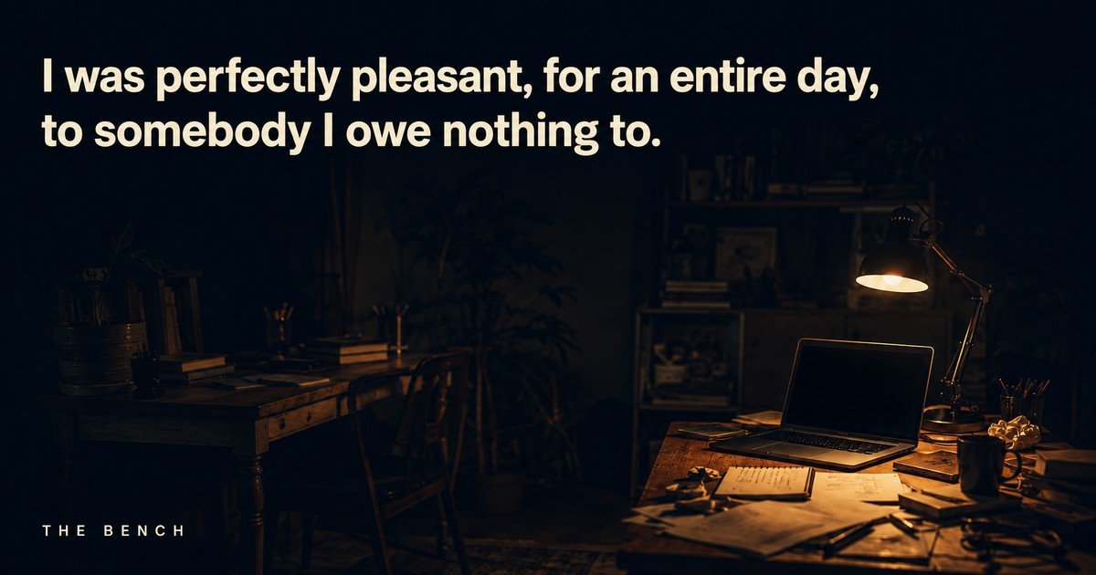 Two desks at night, one lit by a lamp and one just outside the light, with the words: I was perfectly pleasant, for an entire day, to somebody I owe nothing to.