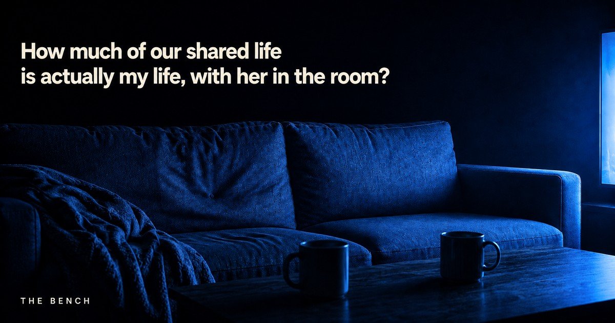 A living room lit only by a television at night, two mugs on the table, with the words: How much of our shared life is actually my life, with her in the room?